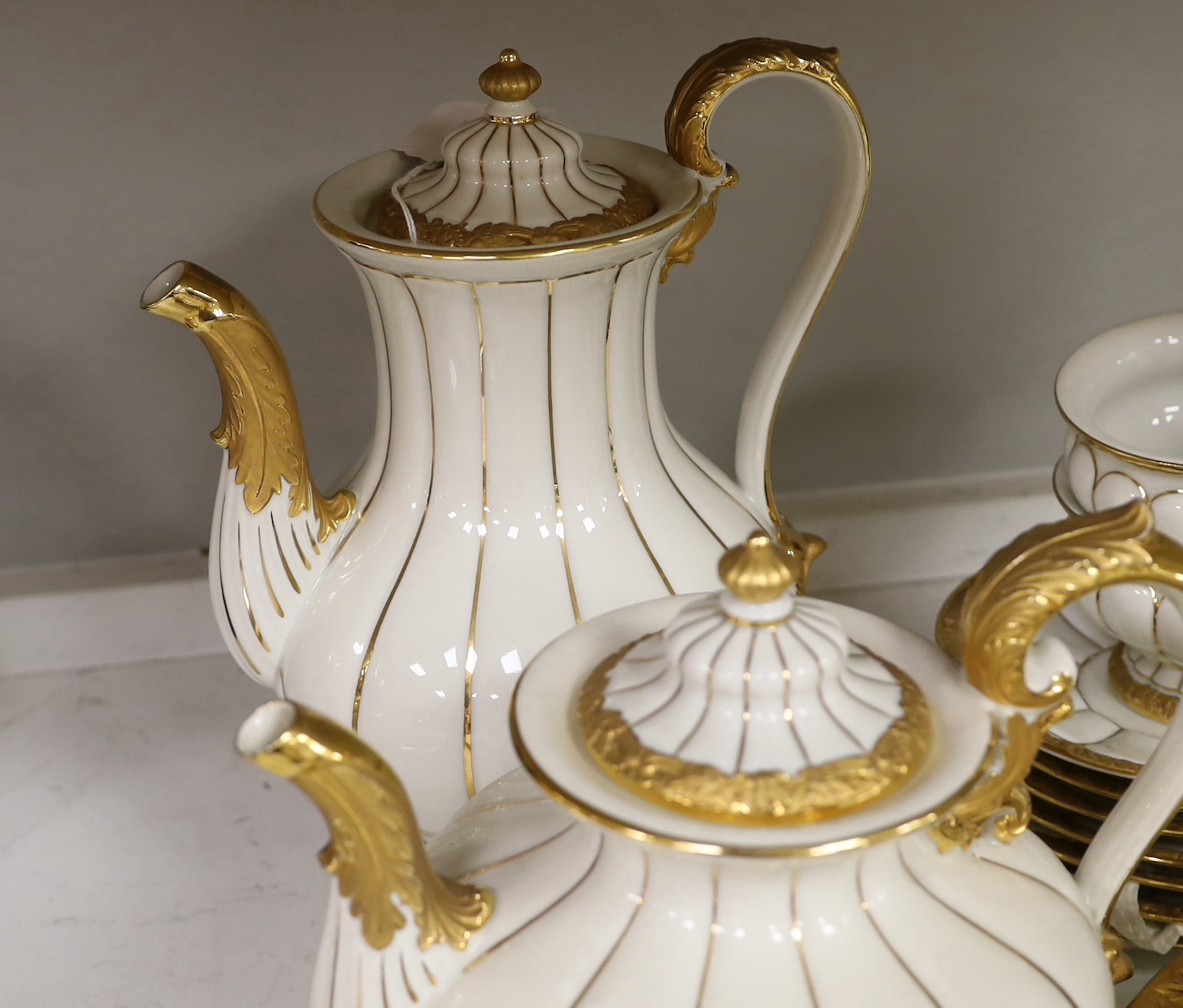 A Meissen gilt and white glazed porcelain tea service, mid 20th century, comprising a teapot, coffee pot, sugar bowl, side plates and seven cups and saucers, coffee pot 28cm